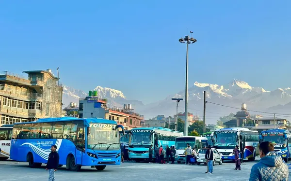 Tourist coaches at Pokhara bus park with the snow-covered Annapurna range behind
